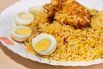 Spicy Indian chicken biryani rice with chicken leg and sliced eggs in closeup macro view