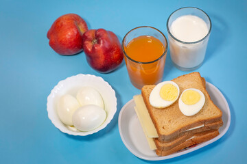Fototapeta premium Healthy Indian breakfast with brown bread, cheese and sliced egg with fruit juice apples and milk in top view