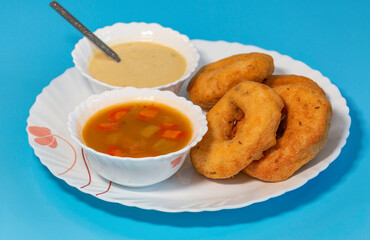 South Indian food of Vada sambar and coconut chutney on blue background in closeup macro view with selective focus