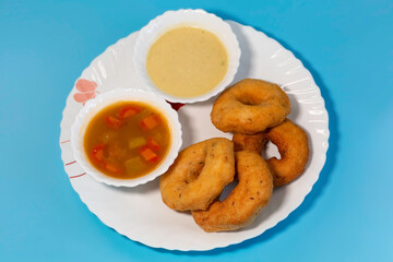 South Indian dish of vada with sambar and coconut chutney on blue background in top view