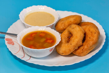 South Indian food of Vada sambar and coconut chutney on blue background in closeup macro view with selective focus	