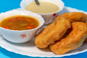 South Indian food of Vada sambar and coconut chutney on blue background in closeup macro view with selective focus