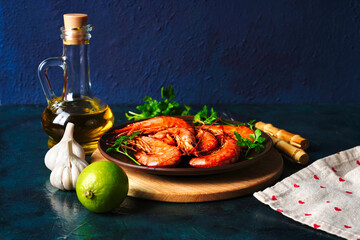 Grilled cooked argentine prawns, shrimps langoustines with herbs, garlic and lemon on a dark...