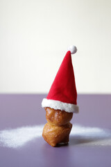 Fried donuts is like a snowman in Santa hat with sugar powder like snow around.