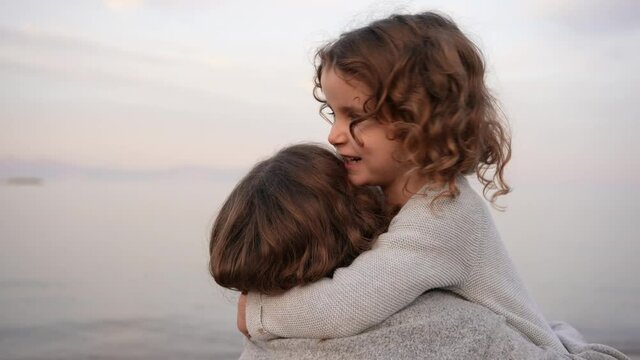 Portrait of a happy laughing girl showing affection to her older sister by hugging and kissing. Happy and carefree childhood concept
