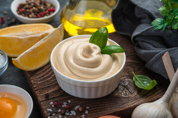 Mayonnaise with fresh basil and ingredients on a dark background.