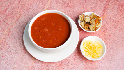 Tomato soup bowl with grated cheese and crackers