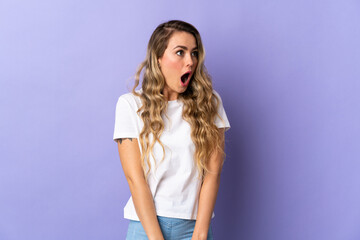 Naklejka premium Young Brazilian woman isolated on purple background doing surprise gesture while looking to the side