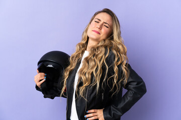 Young Brazilian woman holding a motorcycle helmet isolated on purple background suffering from backache for having made an effort