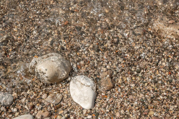 Underwater grey stones background at sea beach. Blurry wet pebble texture on sunny day.