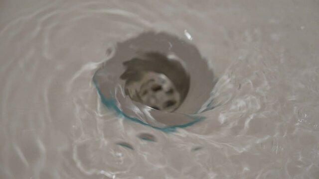 Water flowing down the hole in a kitchen sink. Selective focus. 