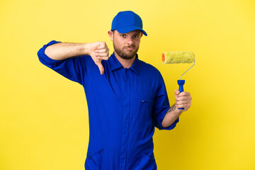 Painter Brazilian man isolated on yellow background showing thumb down with negative expression