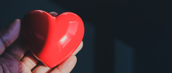 Hand holding red heart on black background, Health care, Life insurance, World heart day, World health day, CSR social responsibility, Valentine background concept