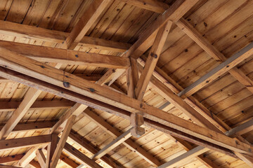 Roof overlap. Roof structure from the inside. Wooden beams, rafters and joists.  - obrazy, fototapety, plakaty