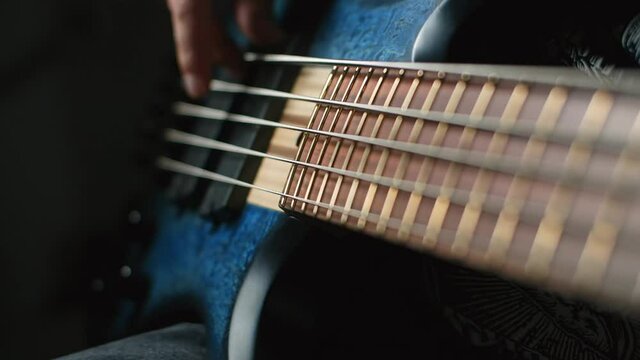Bassplayer plays with his fingers on the modern 5 string bass in slow motion, 1080p 240fps