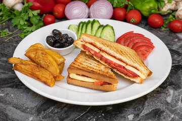 Toast with cheddar cheese, sausage and tomato with french fries and salad on marble table