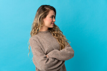 Young Brazilian woman isolated on blue background looking to the side