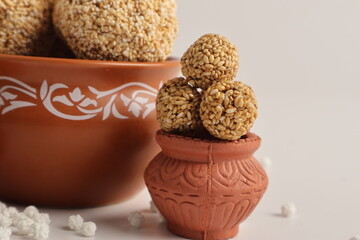 Til Gul OR Sweet Sesame seed ball or Laddu with Fikri for Indian festival Makar Sankranti over white background.