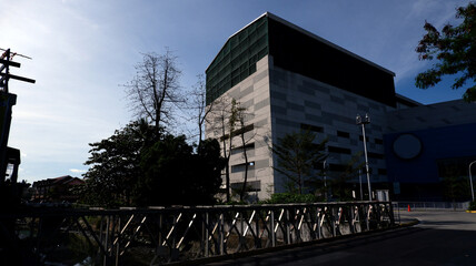 Fototapeta premium Old steel bridge and iconic railings over a stinking polluted river leading to a huge commercial building