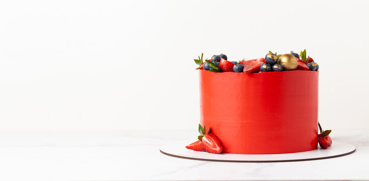 Red cake with cream cheese frosting for a big event. luxurious cake with golden decoration and berries on top on the white background