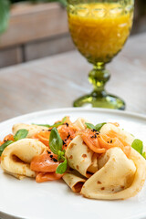 pancakes with salmon decorated with fresh herbs, served with juice. breakfast, photo of the dish in the interior