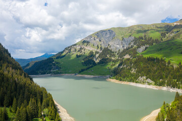 The lake and the Dam of Saint Guerin in Europe, in France, towards Beaufort, in the Alps, in summer, on a sunny day.