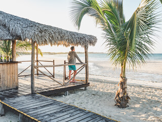 Handsome man on the beach against the background of the sea, looking into the distance. Outdoors, closeup. Concept of leisure and travel