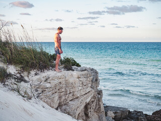 Handsome man standing against the backdrop of a rock and look into the distance. Outdoors, closeup. Concept of leisure and travel