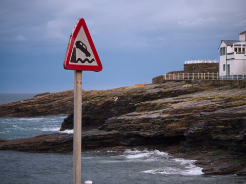 Horizontal view of warning traffic sign of end of road and fall into the sea and Ringlo village in the background.