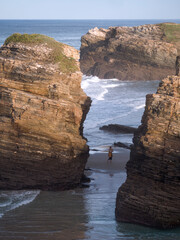 Naklejka premium Las Catedrales beach, Ribadeo, Galicia, Spain. Female tourist making photos surrounded by cliffs.