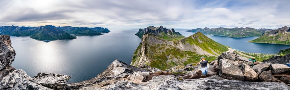 Man with camera photographing Hesten and Inste Kongen mountains standing on Segla peak, Senja island, Troms county, Norway, Scandinavia