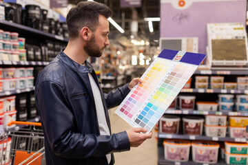 a man in a hardware store with a palette of paints for wall decoration in his hands concept of...