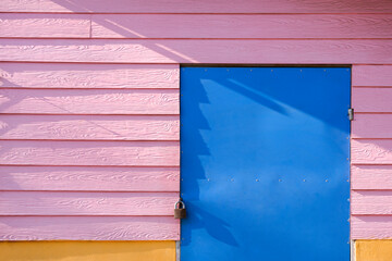 Front view of blue prefabricated door and pink artificial wood with yellow cement wall of vintage coffee street kiosk