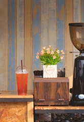 Iced lemon tea in plastic glass with straw box and coffee machine on wooden counter of vintage coffee shop in vertical frame