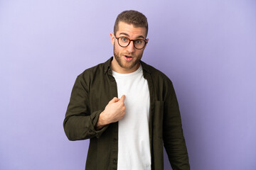 Young handsome caucasian man isolated on purple background pointing to oneself