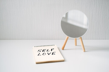 Self love, state of appreciation for oneself, physical, psychological and spiritual growth, taking care of own needs, wellbeing. Notepad with text Self love and reflection in the mirror