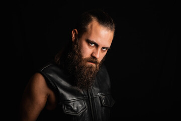 Portrait of a bearded, biker man in a leather vest 