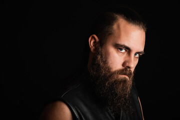 Portrait of a bearded, biker man in a leather vest 
