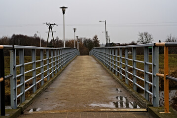 Mostek  kładka dla pieszych , z barierkami , nad rzeką Kamienną . Bridge on a pedestrian footbridge, with barriers, on a Stone river.  - obrazy, fototapety, plakaty