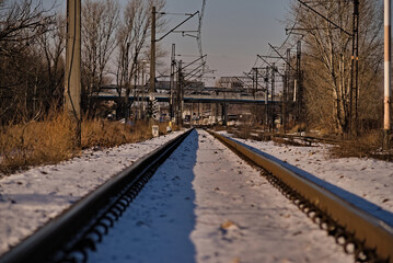 Tory kolejowe ( szyny) w śniegu, biegnące w stronę wiaduktu .