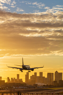 Aircraft landing at London City Airport at sunset, with Canary Wharf and O2 Arena in background, London