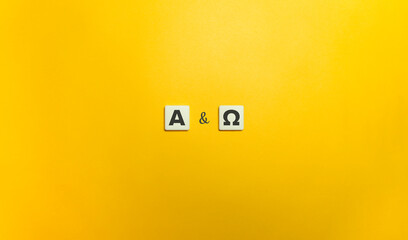From Alpha to Omega Concept. Block Letter Tiles on Yellow Background - obrazy, fototapety, plakaty