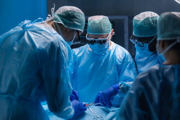 Multiracial team of professional medical surgeons performs the surgical operation in a modern...