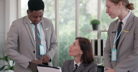 Walking into the meeting and saying hello to colleagues, an African-American airline business manager meets with Caucasian workers to examine the airline company's prediction plan. - Powered by Adobe