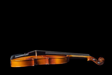 Naklejka na ściany i meble Side view of a violin lying on a black background.