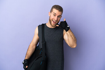 Young sport man with sport bag isolated on white background making phone gesture. Call me back sign