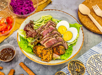 Fresh tuna Tataki salad, lettuce, avocado, boiled eggs, and dip. Tasty seafood salad of Japanese cuisine in a bowl on marble background top view