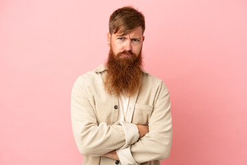 Fototapeta premium Young reddish caucasian man isolated on pink background feeling upset