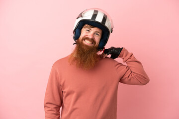 Young reddish caucasian man with a motorcycle helmet isolated on pink background laughing