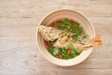 spicy boiled fried red bass fish and  herb in tom yum soup on bowl